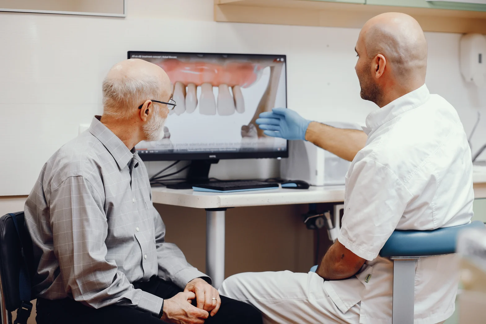 Dentist showing a dental implant model to a patient in Brooklyn
